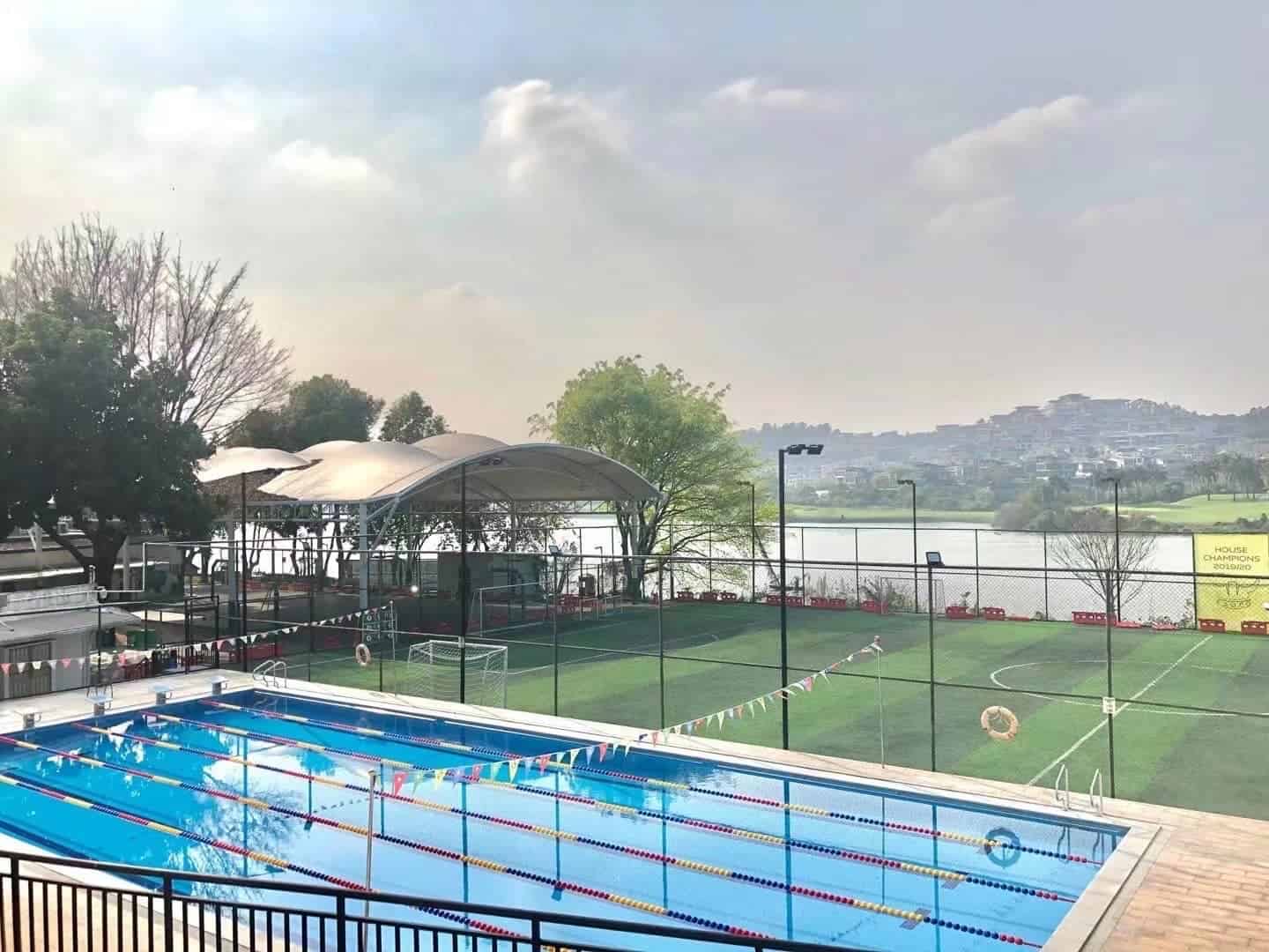 Modern school sports facilities including swimming pool and soccer field at World Schools.