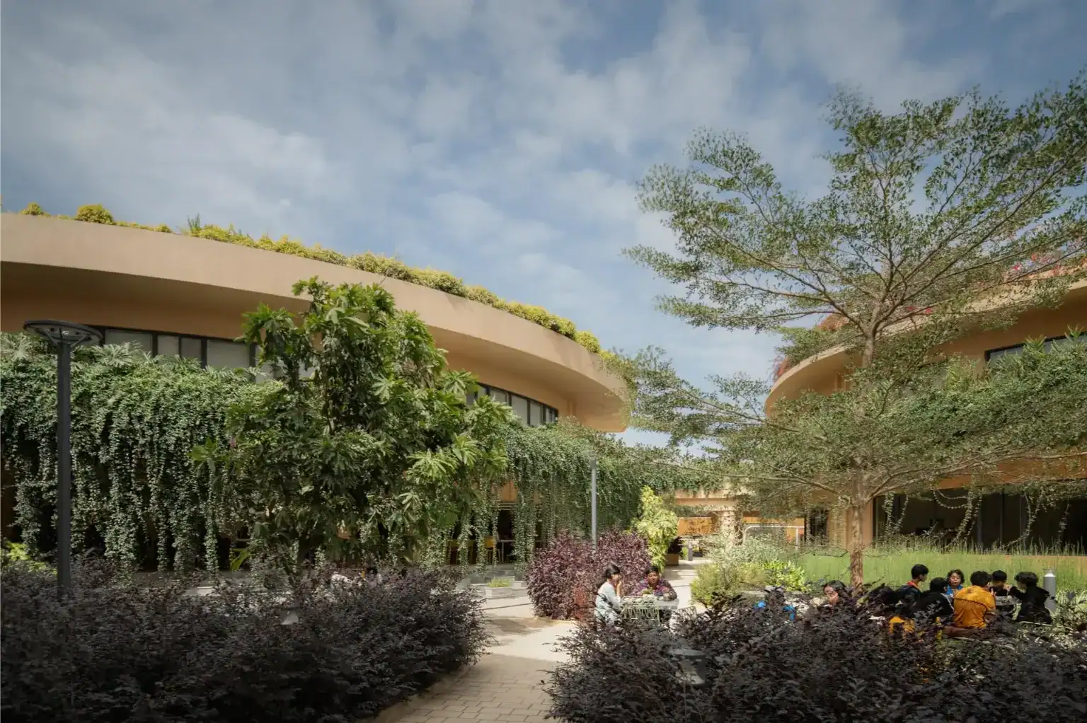 Modern school campus with lush greenery and outdoor seating areas for students.