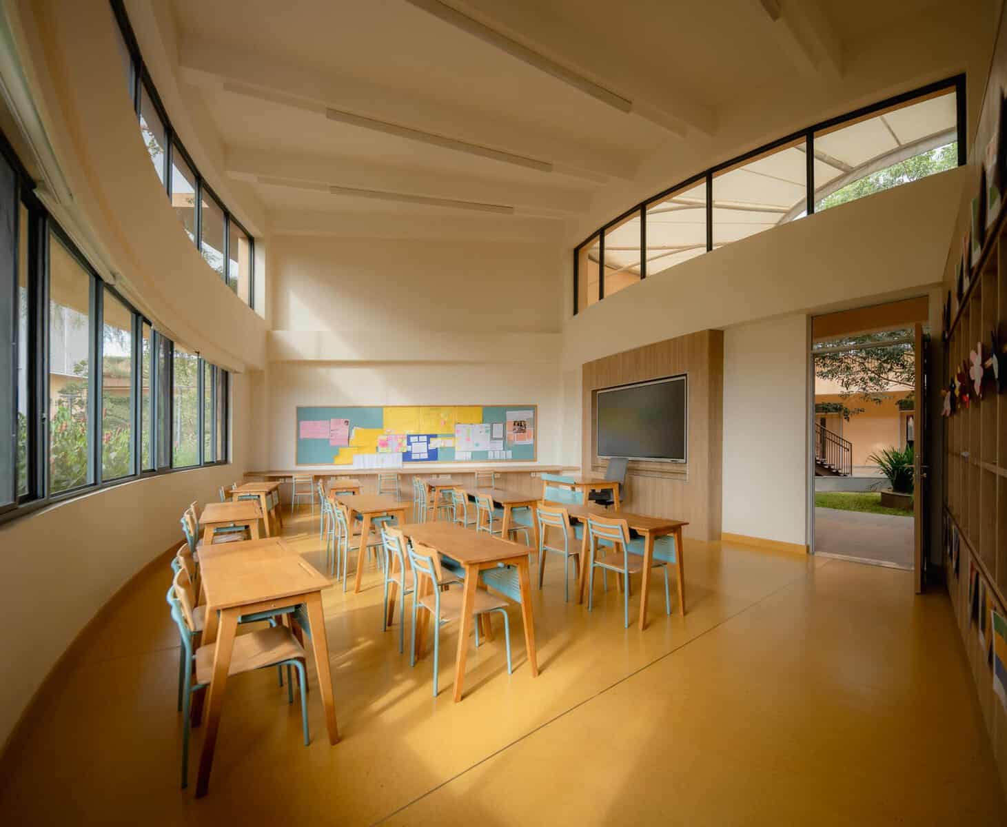 Modern classroom with large windows and wooden desks in a bright, airy school setting.