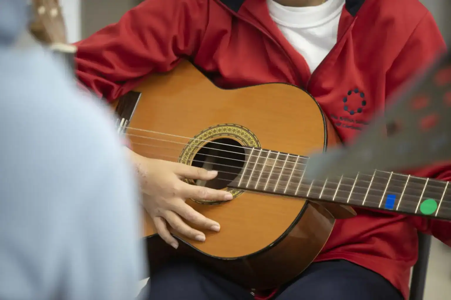 ACOUSTIC GUITAR STRUMMING AT SCHOOL, PROMOTING MUSIC EDUCATION AND CREATIVE ARTS.