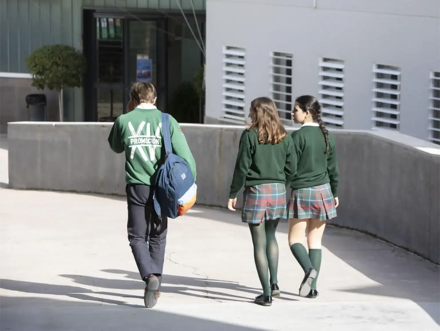 Students walking outside of a school building wearing uniforms, promoting international education.
