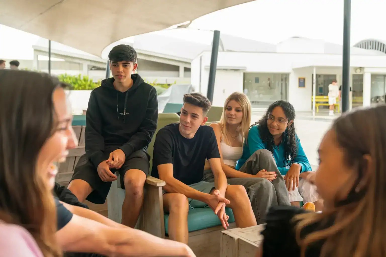 Teenagers engaging in conversation at a modern international school campus.