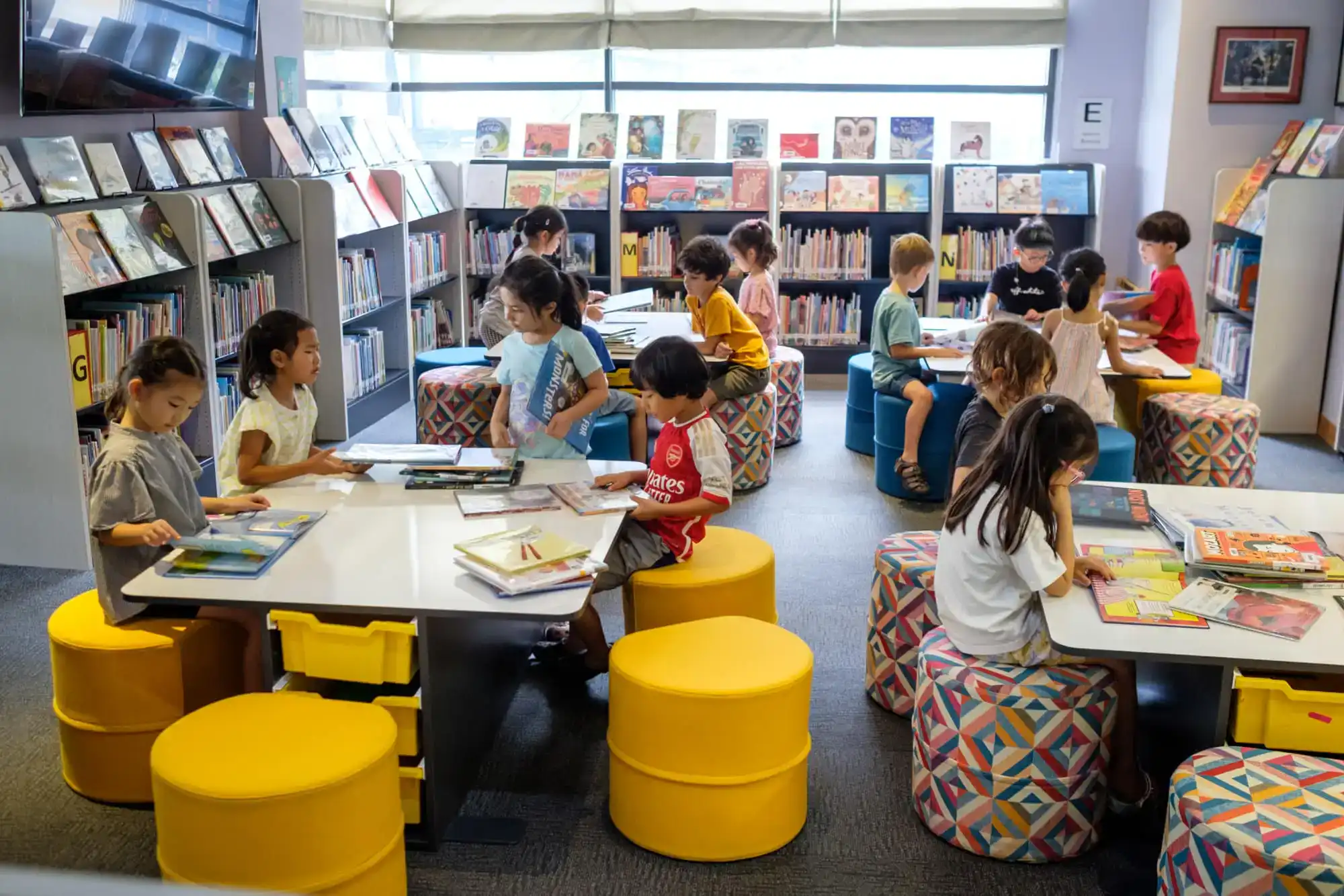 Colorful children's library with kids reading and exploring books in a bright, modern learning environment.