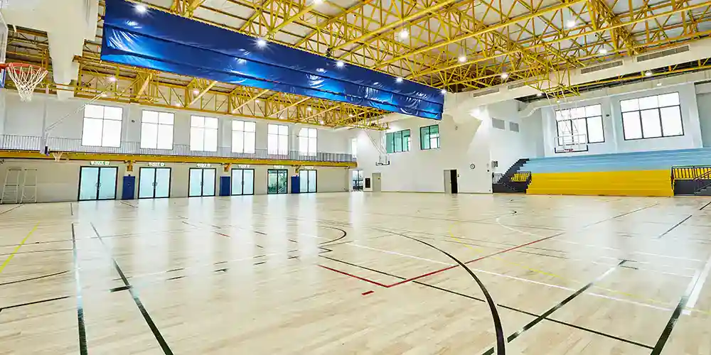 Vast indoor gymnasium at World Schools, equipped for sports and physical education activities.