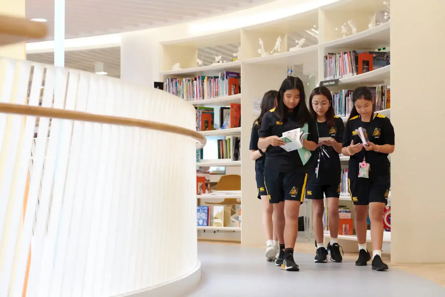 Students reading books in a modern school library, promoting learning at world schools for optimal education.