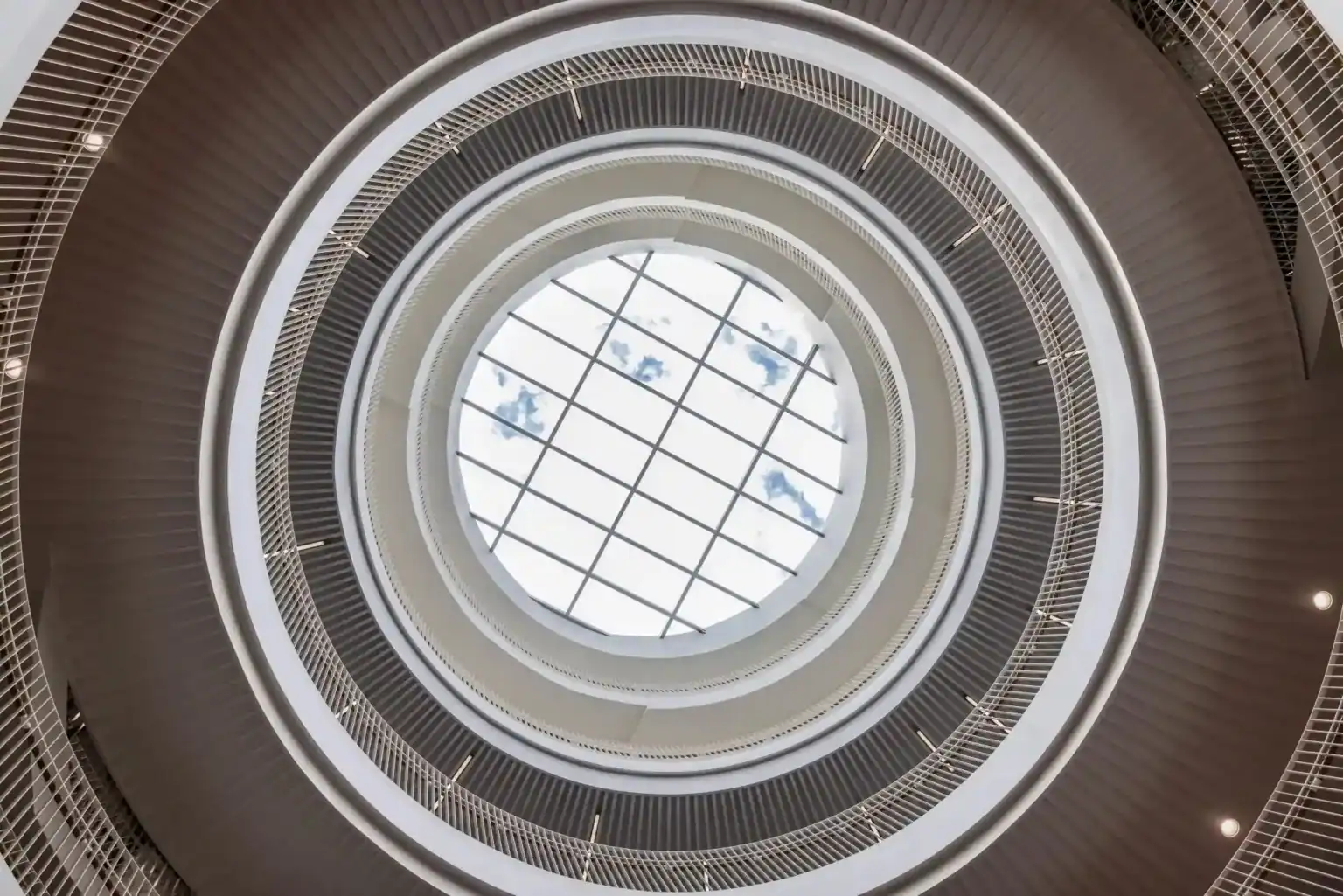 Bright circular atrium with a glass skylight, modern architecture, and multiple levels, emphasizing innovative school design.