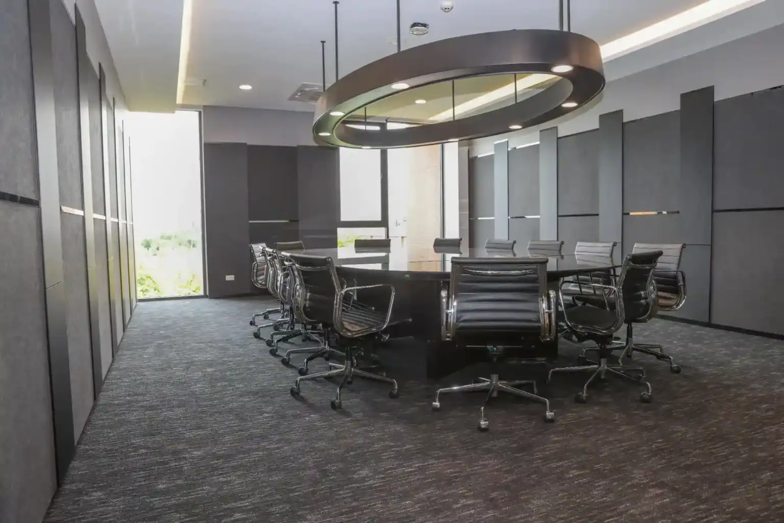 Modern conference room with black chairs and round table, ideal for business meetings and seminars.