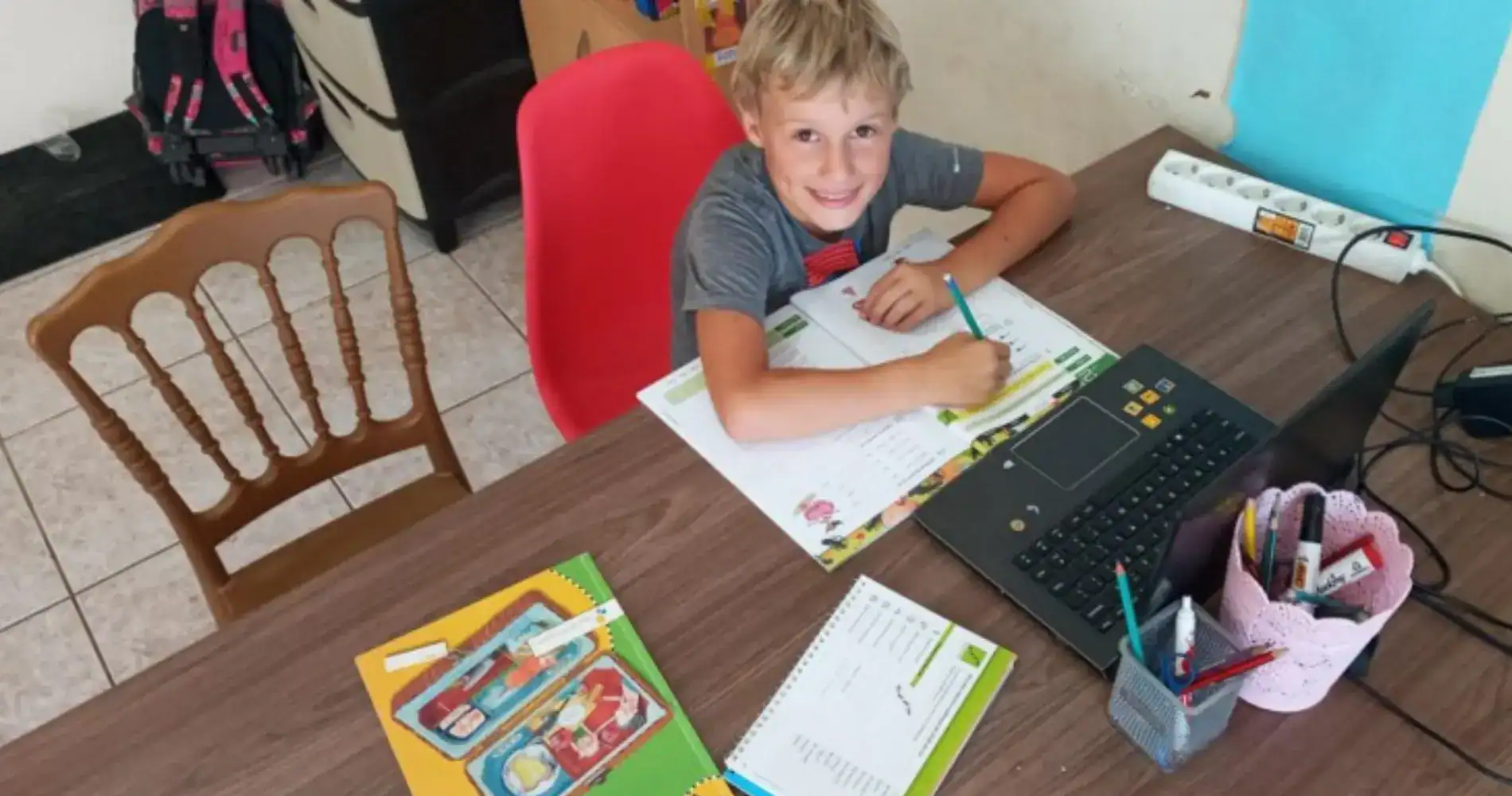 Bright young student engaged in online learning at home, studying with educational materials.