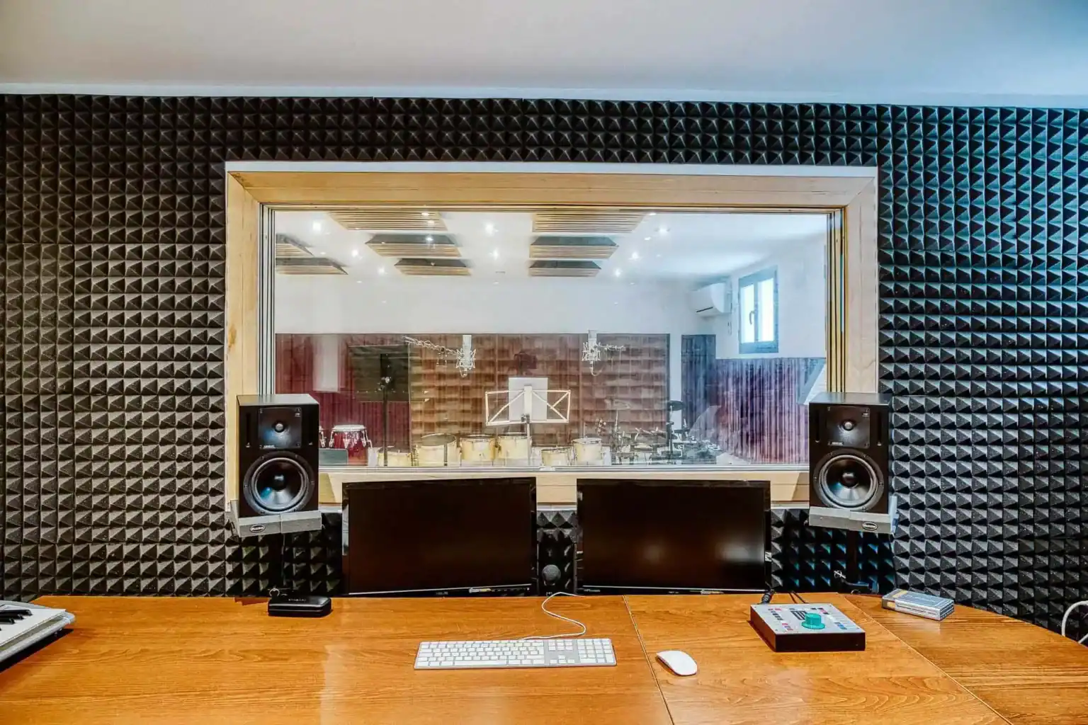 Modern school recording studio with acoustic foam panels and audio equipment for music production.