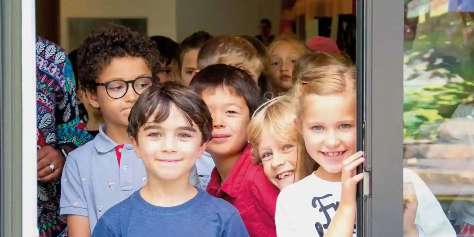 Diverse group of happy school children looking through a window, engaging in a learning environment.