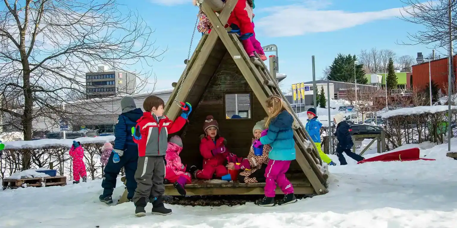 Children playing outdoor in snowy playground at winter, school children having fun in snowy outdoor activity.