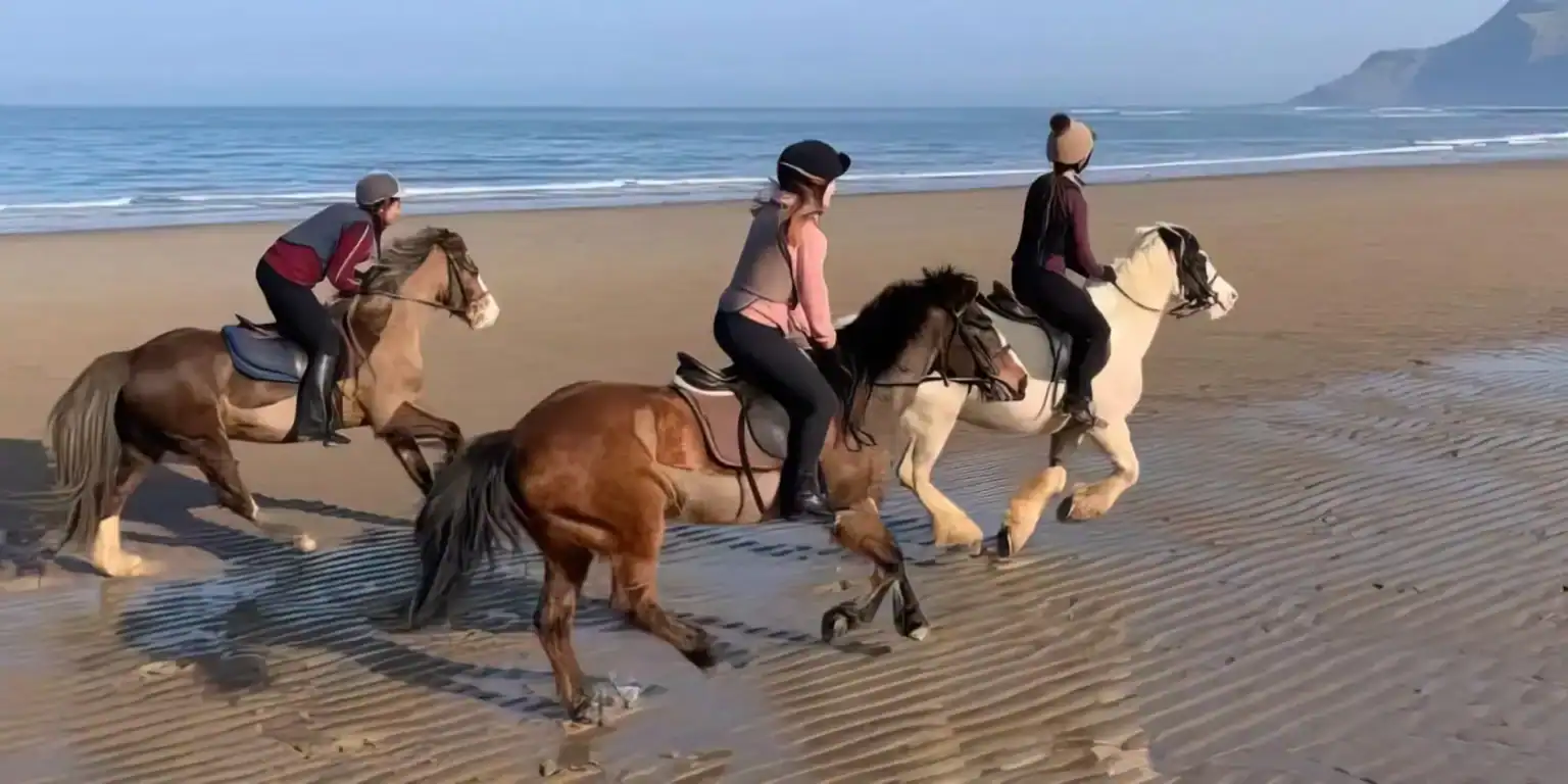 Bambini a cavallo sulla spiaggia, attività all'aperto con vista panoramica sull'oceano.