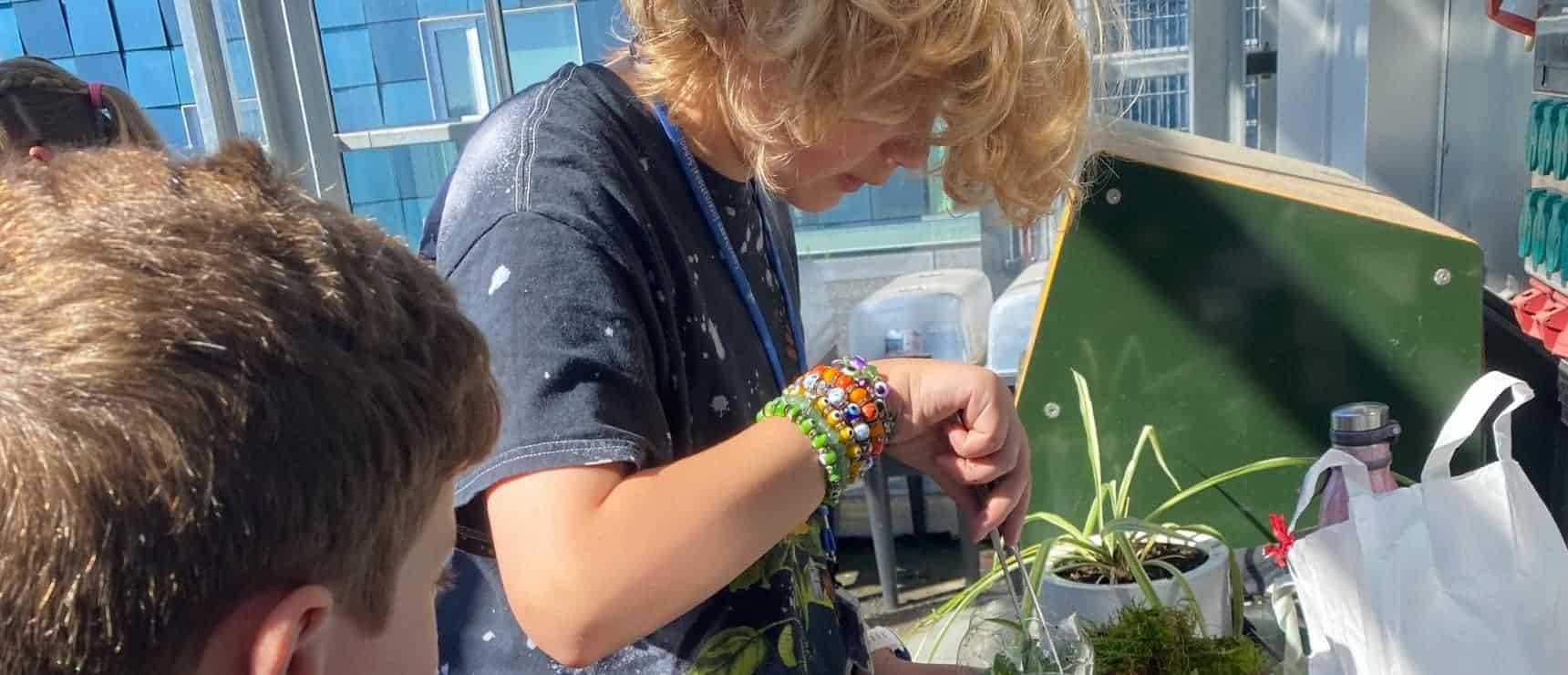 5 Tips for Schools to Create Successful Sustainability Practices 8 Young girl tending to plants in an educational greenhouse, fostering STEM and environmental skills.