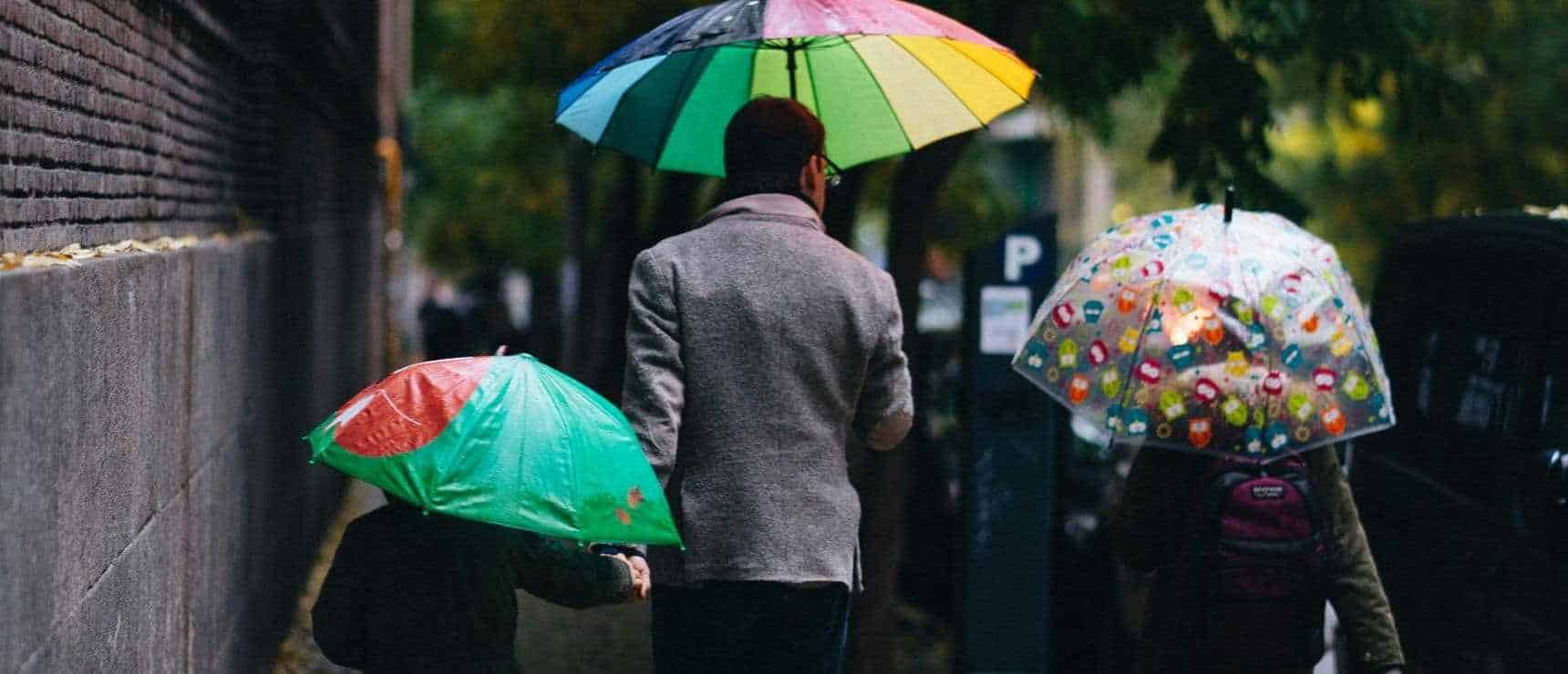 Colorful umbrellas in rainy city street with people walking, showcasing weather resilience and urban life.
