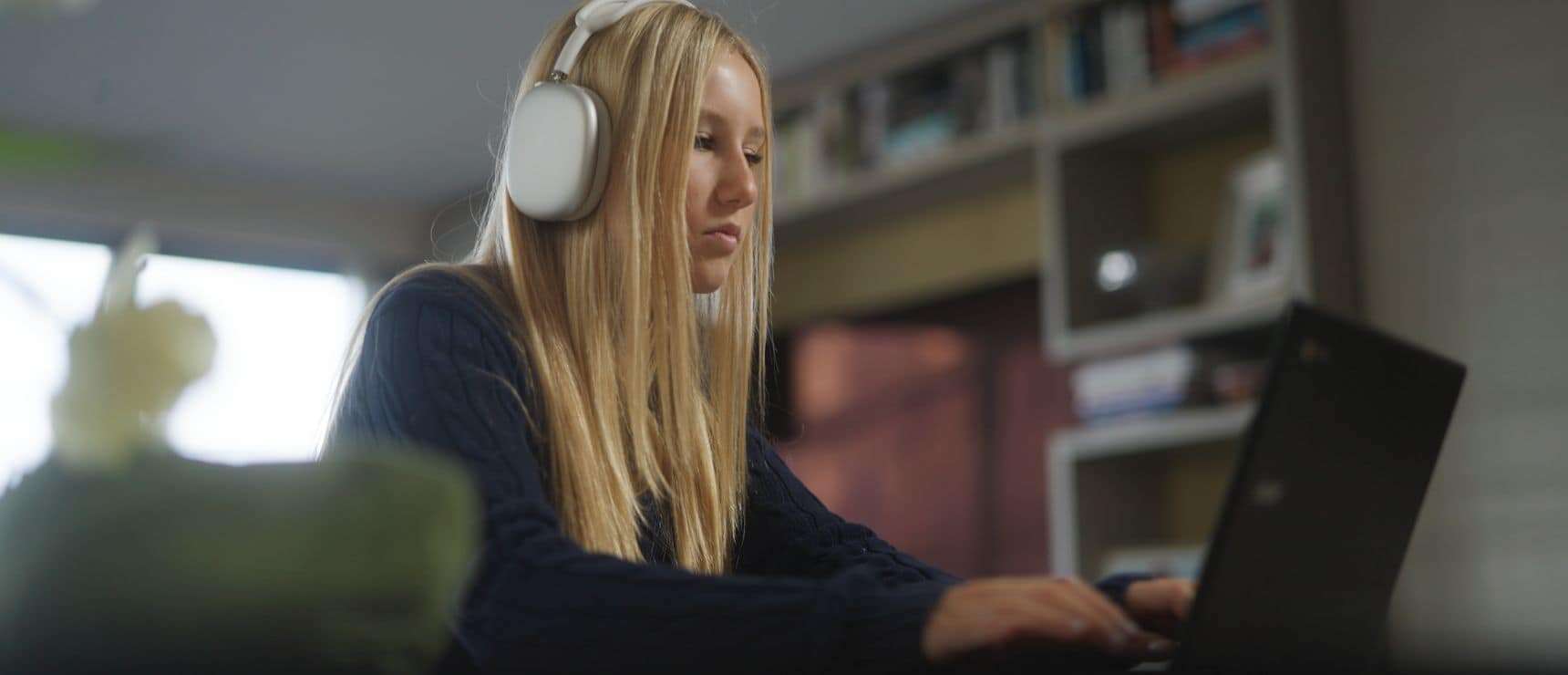 Young girl focused on online learning with headphones in a modern classroom or home setting.