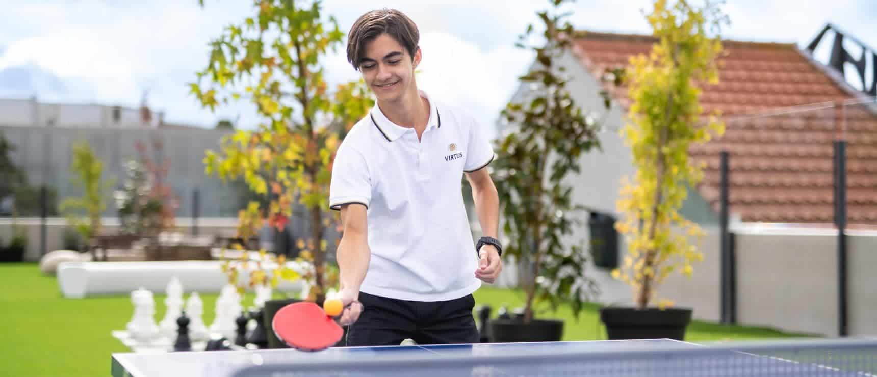 Energetic student playing ping pong outdoors at a World Schools event.