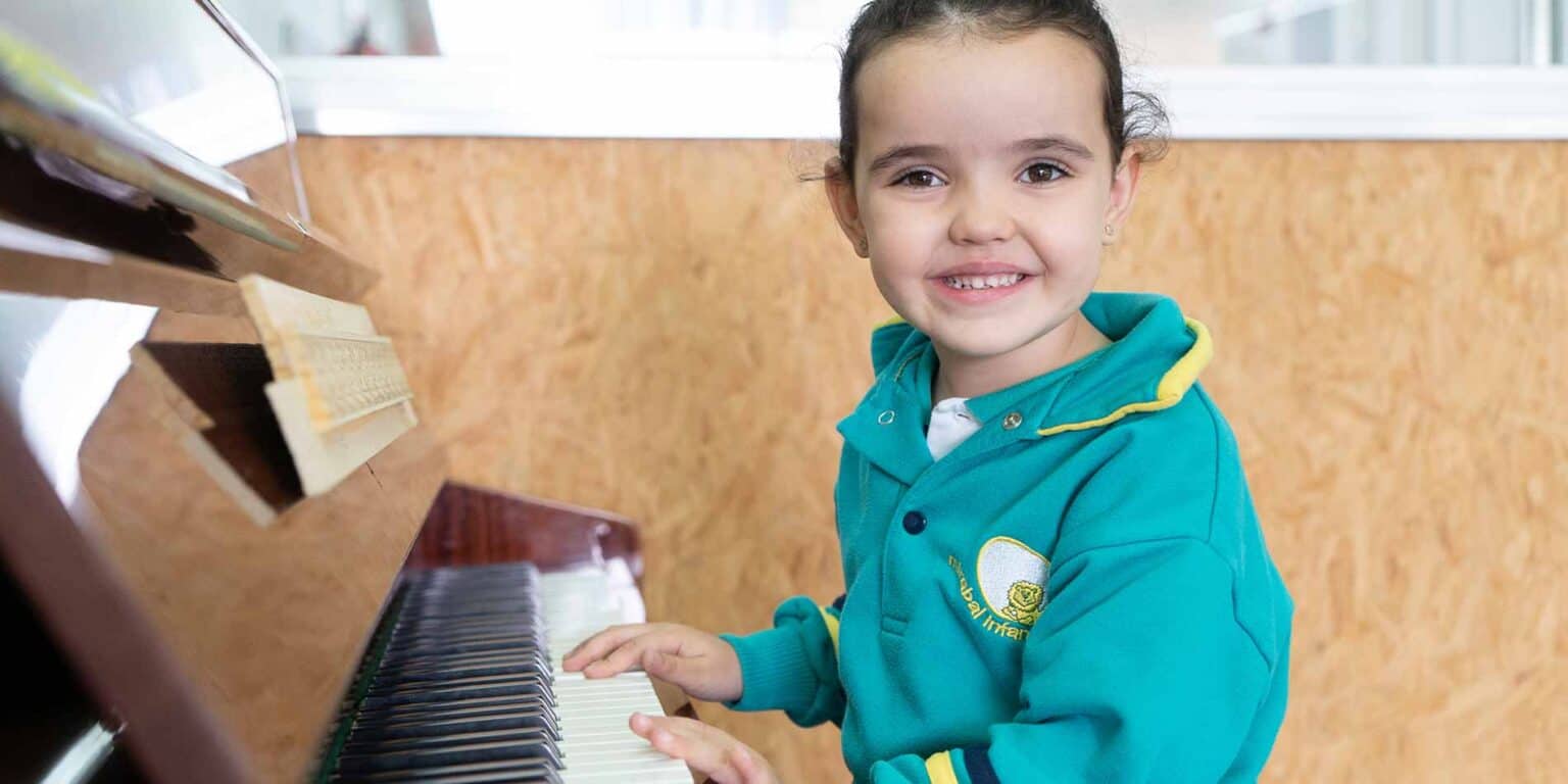 Bright young student playing the piano at World Schools, highlighting quality education and musical development.
