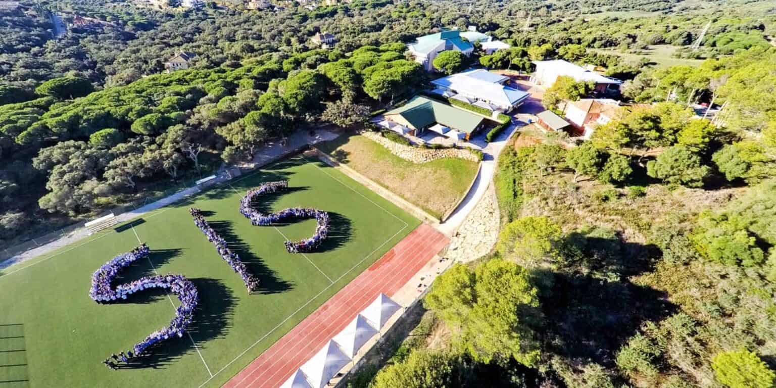 Aerial view of World Schools campus with lush greenery, sports fields, and modern buildings in a serene setting.