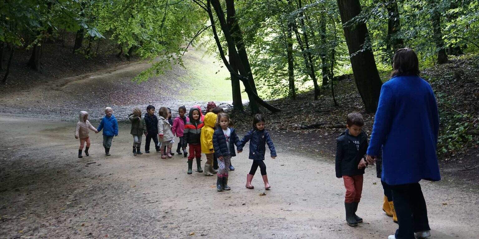Children exploring nature during outdoor educational activity in a forest.