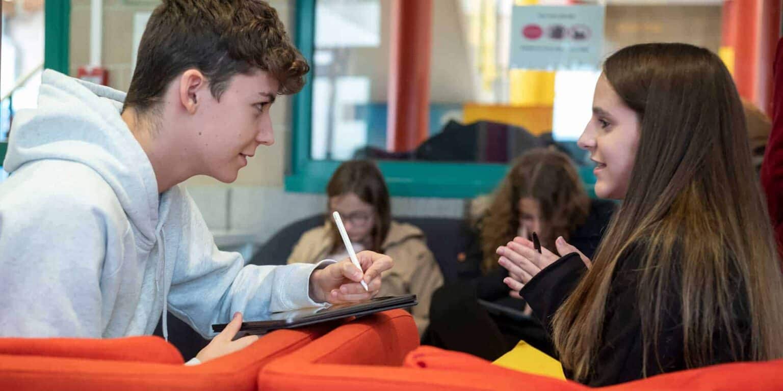 Focused teenage students engaging in a friendly conversation at a international school.