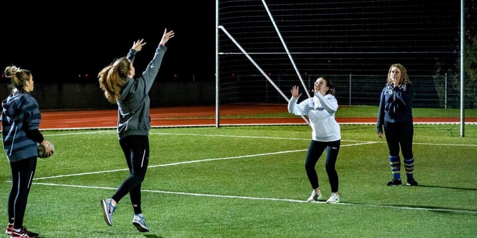 1. Girls playing volleyball at a world school sports event during night.