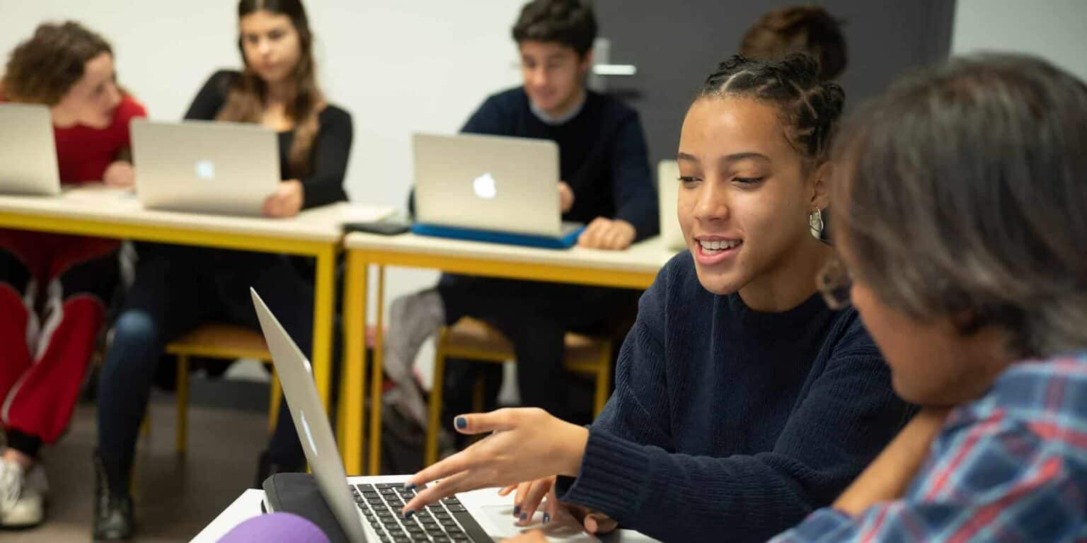 Innovative learning at a world schools classroom, featuring diverse students engaged with laptops.