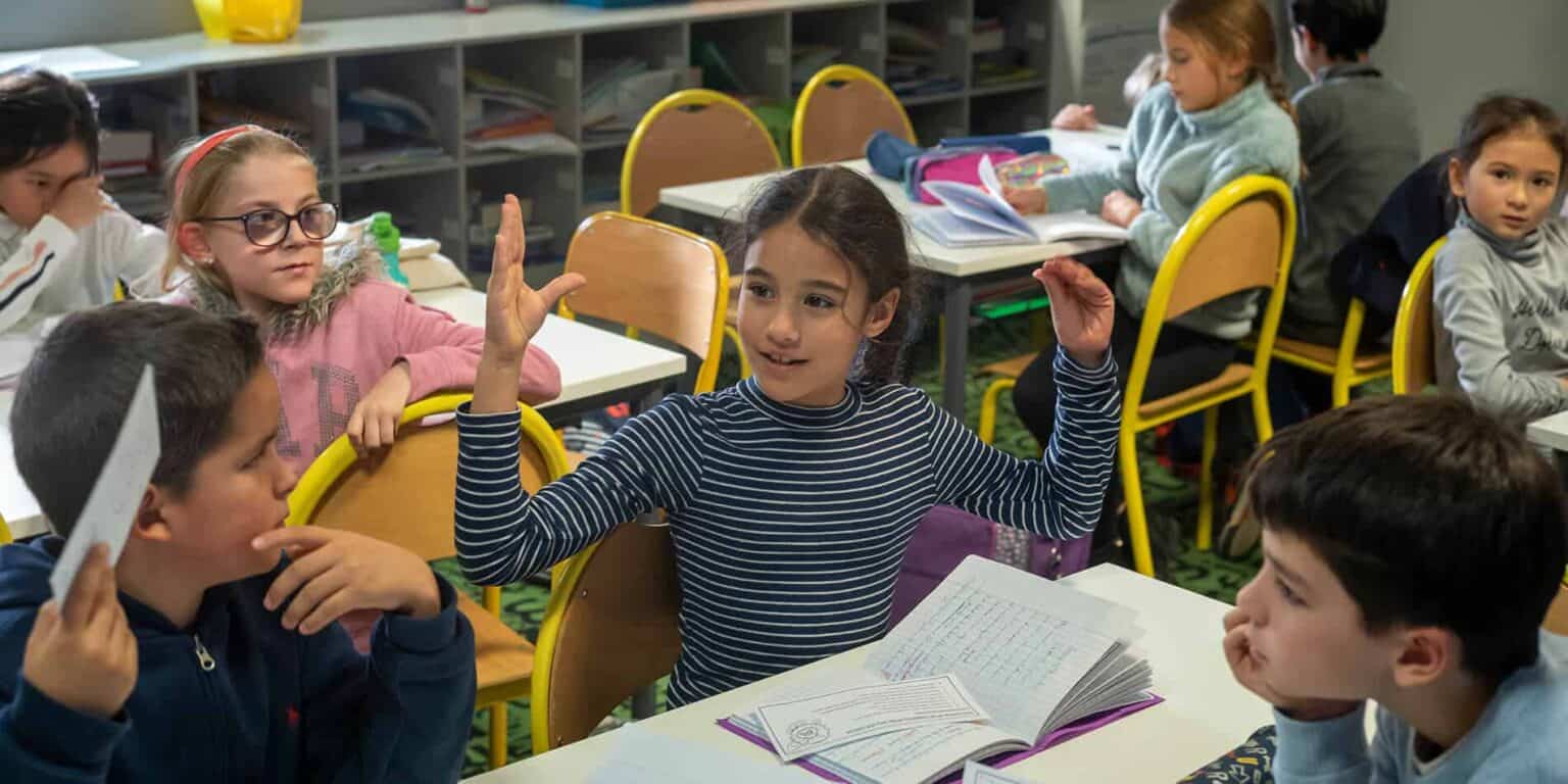 Young students engaging in classroom discussion at an international school.