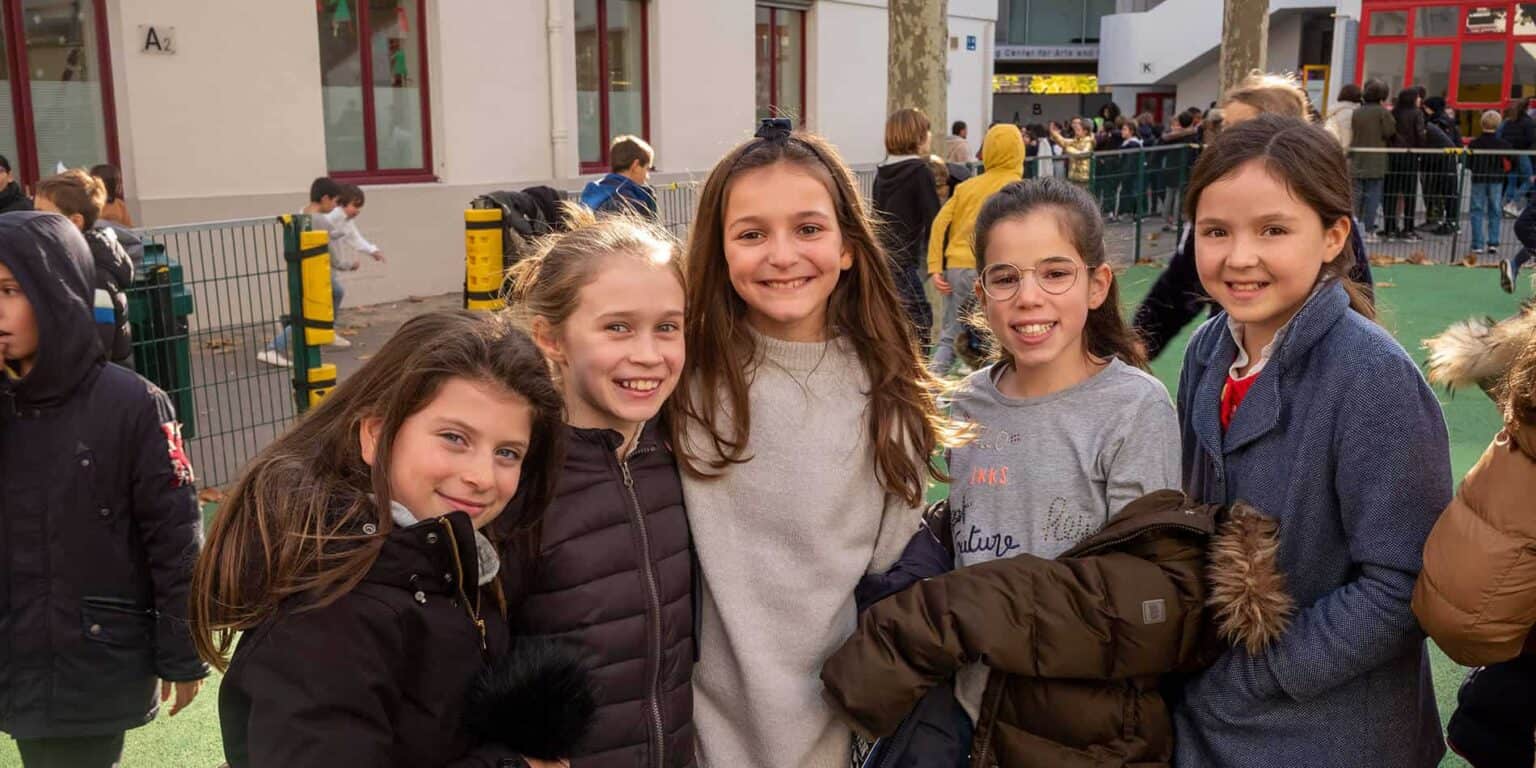 Colorful school children smiling outdoors at a World Schools educational event.