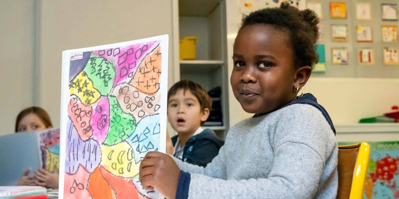 Colorful children's artwork displayed in a classroom with young students engaged in creative activities.