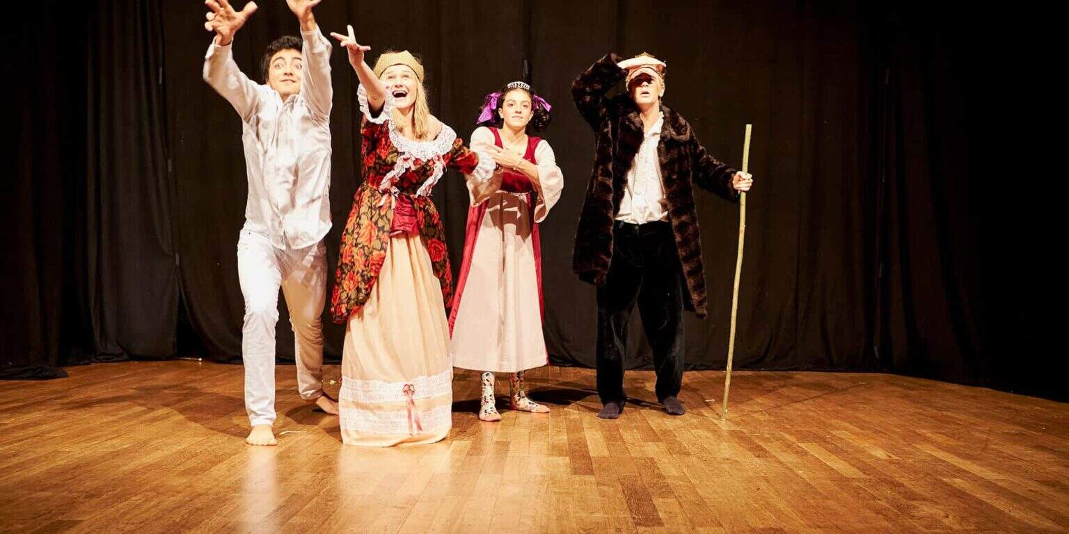 أطفال يؤدون على خشبة المسرح في مسرحية مدرسية، مرتدين أزياء للإنتاج المسرحي.