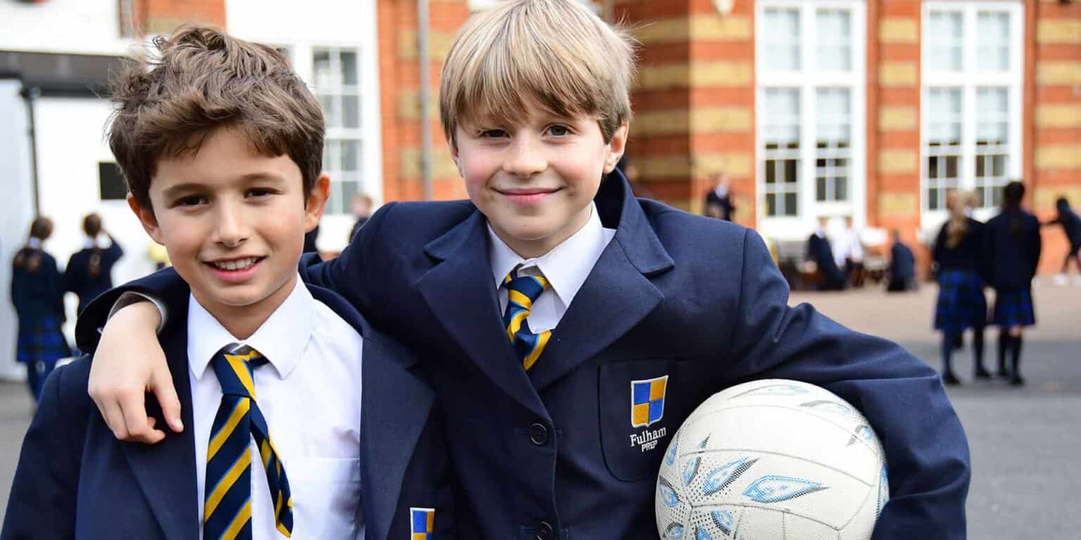 Bright schoolboys in uniform smiling with a soccer ball at Fulham Pre-Preparatory School, showcasing quality education and student camaraderie.