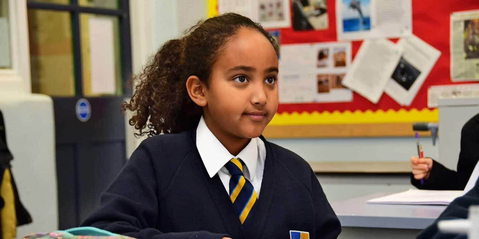 Young girl in school uniform attending class at an international school, focusing on learning and academic success.