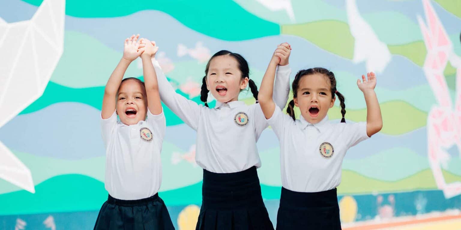 Smiling children in school uniforms celebrating achievement at World Schools event.