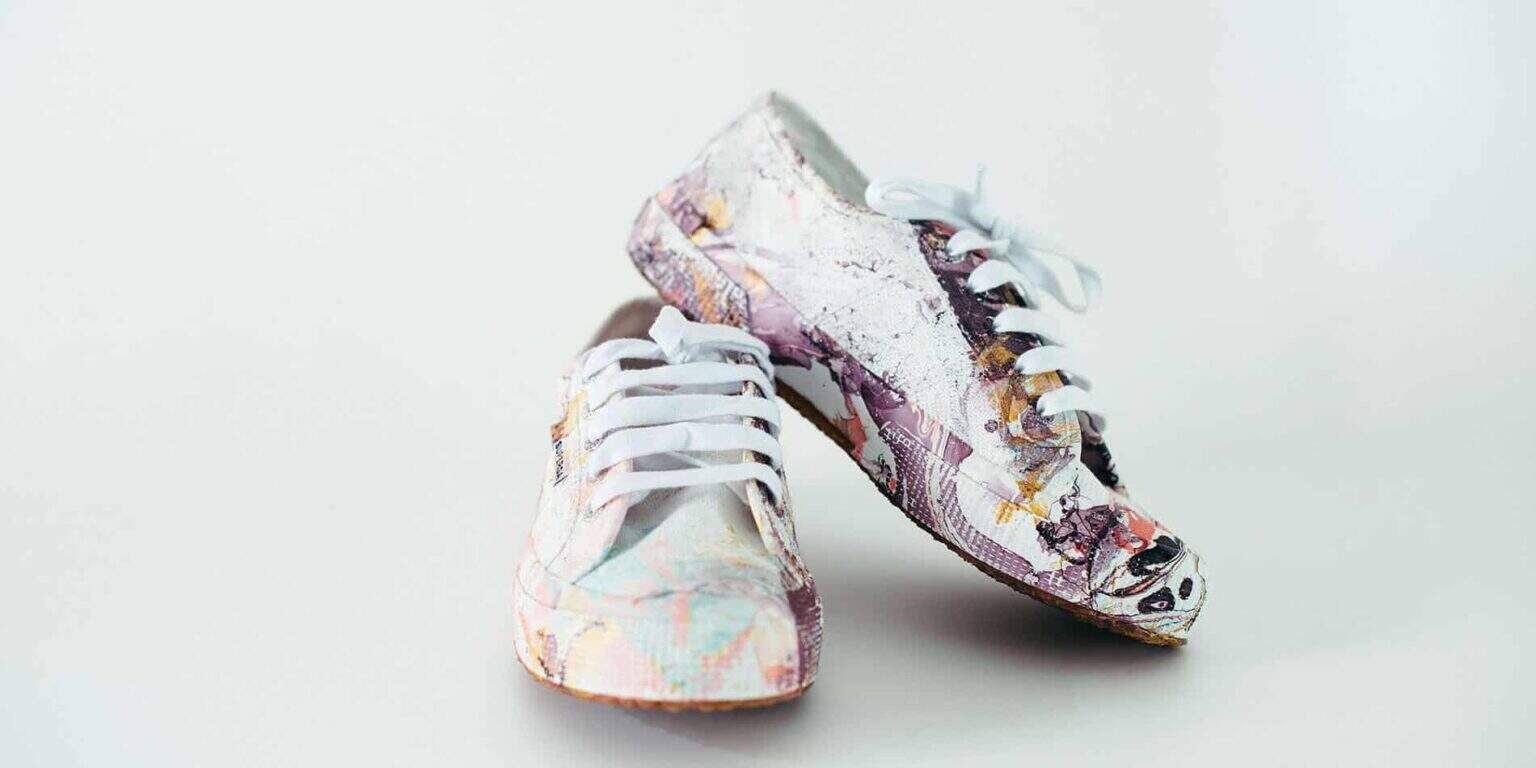 Colorful artistic sneakers with dollar bill prints, creative fashion statement.