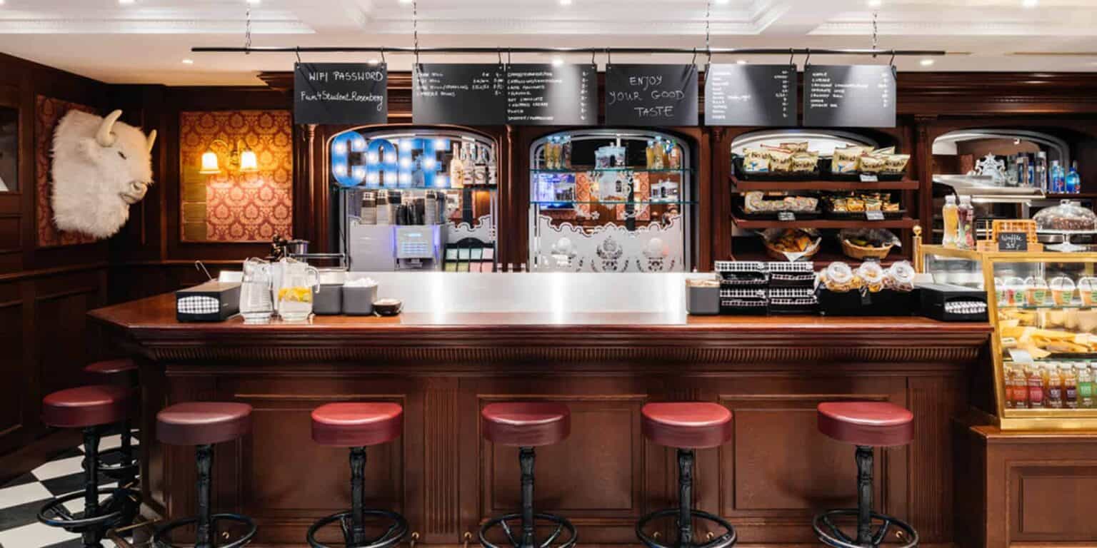 Cozy cafe with dark wood furnishings, bar stools, and a variety of snacks and drinks on display.