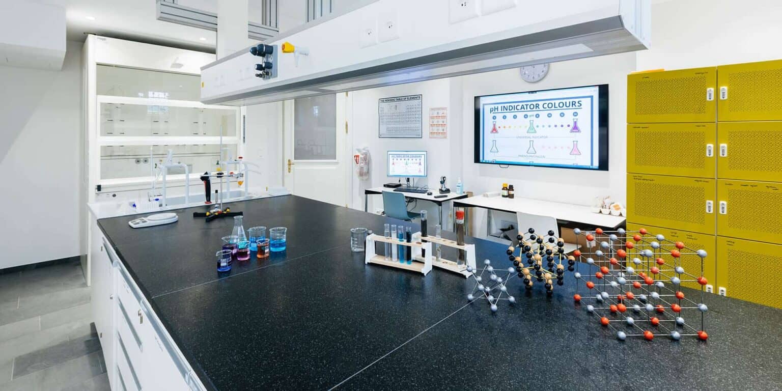 Laboratory science classroom with pipettes, test tubes, molecular models, and digital displays for educational purposes.