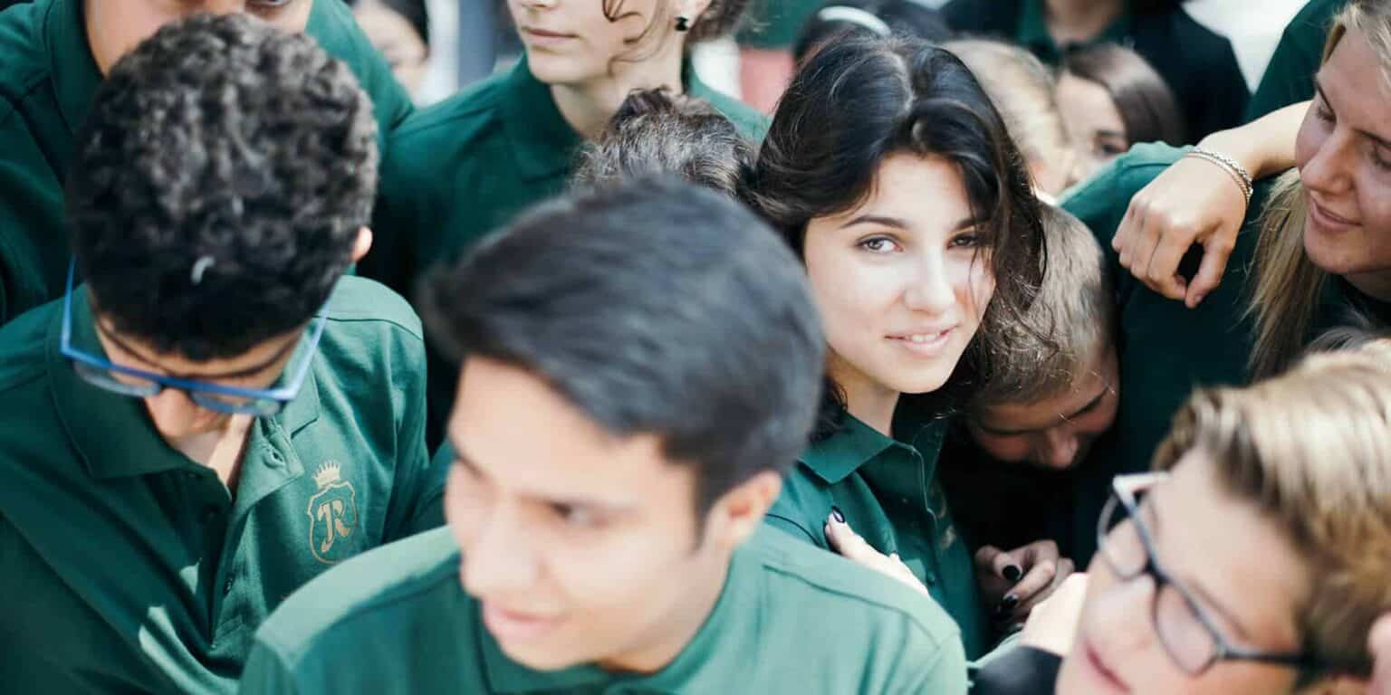 Diverse group of students wearing green uniforms at World Schools, collaborative learning environment.