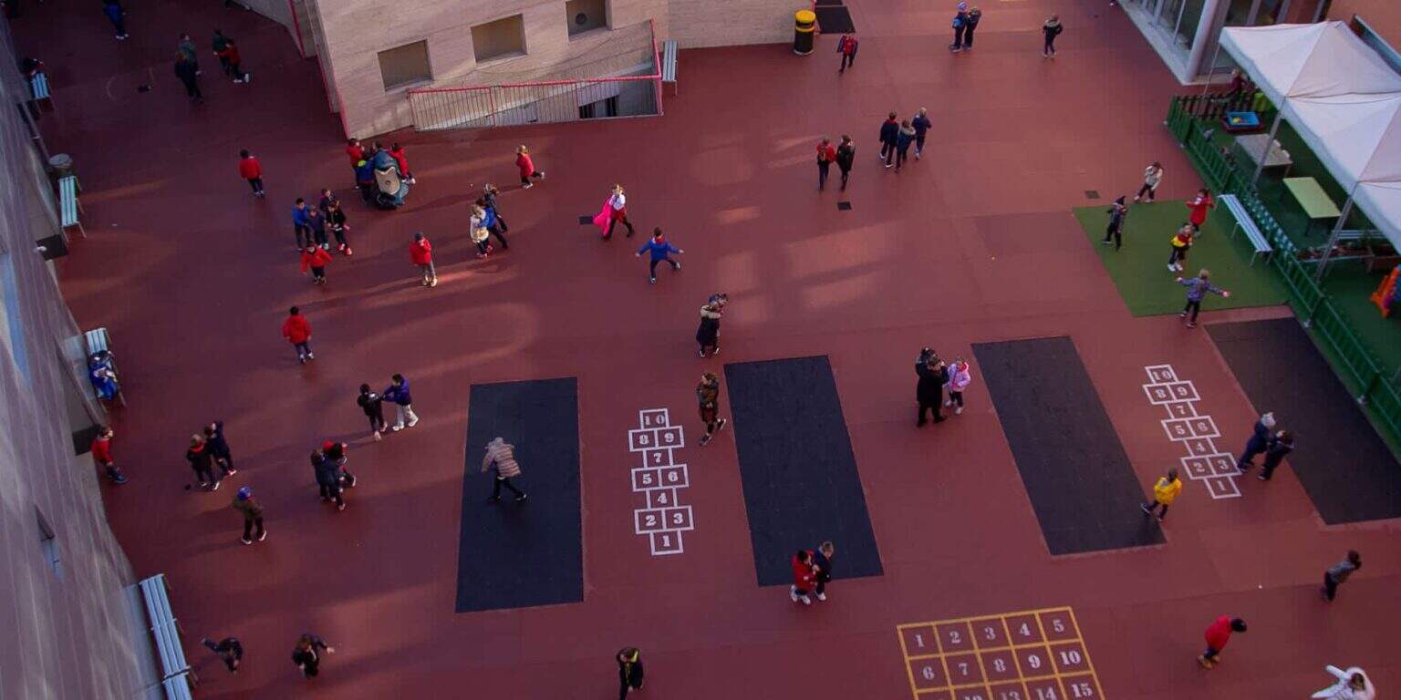 Colorido patio escolar con niños jugando y disfrutando de actividades al aire libre, ideal para la educación primaria global.