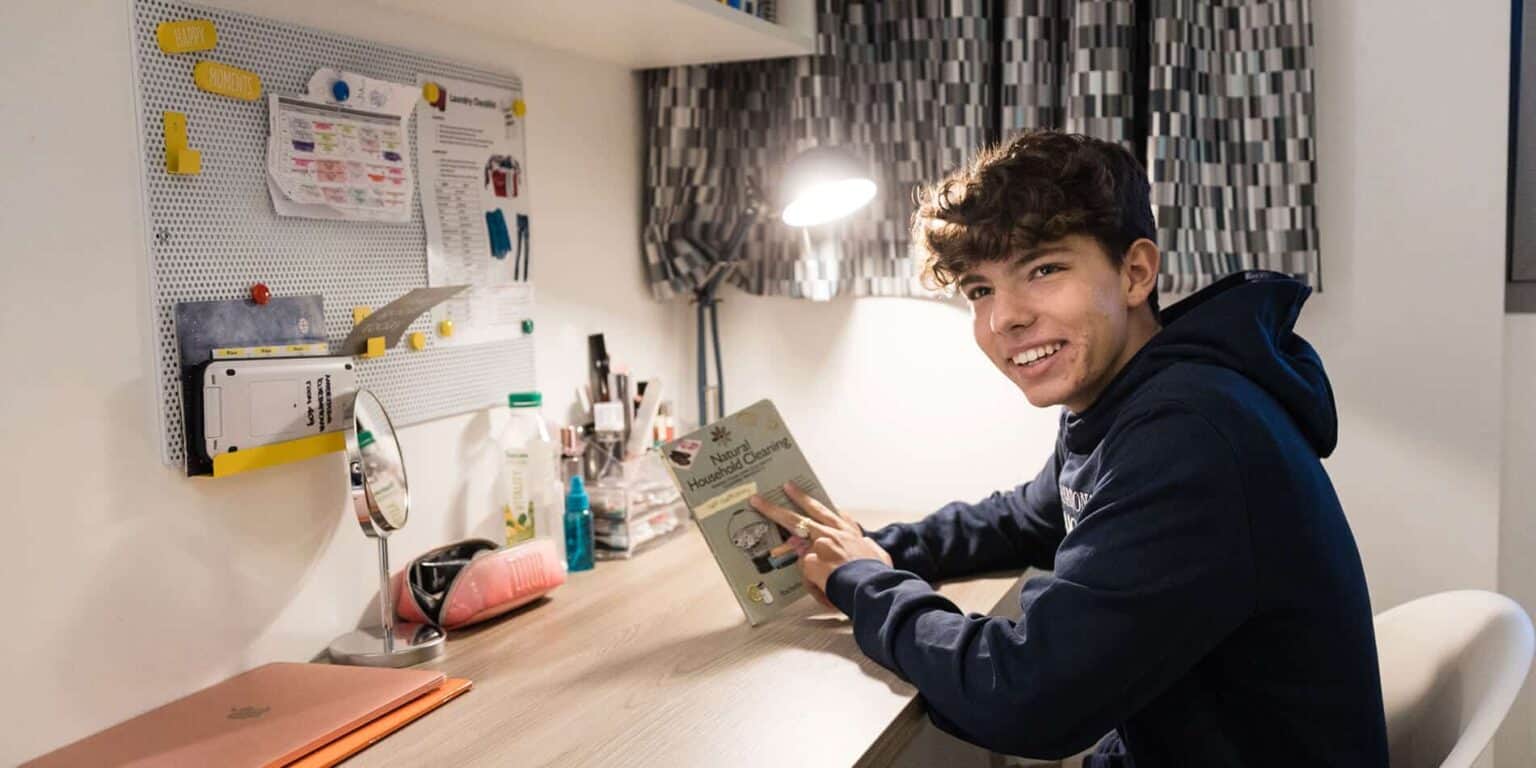 Young student studying homeschooling guide on desk with educational materials and organized workspace.