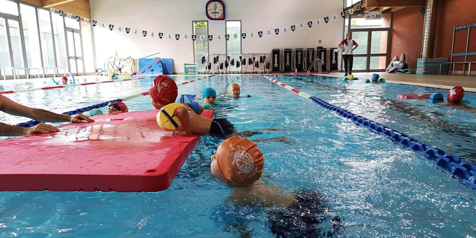 Bright indoor swimming pool with children swimming and practicing aquatic skills at a world school.