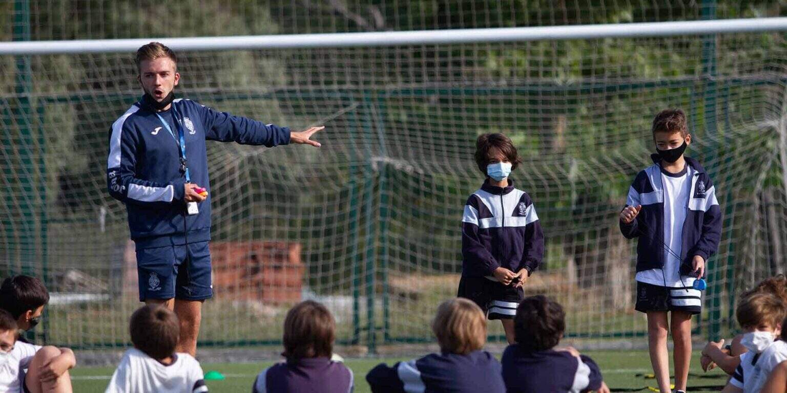 Sports coaching session with children at a school football field, promoting physical activity and teamwork.