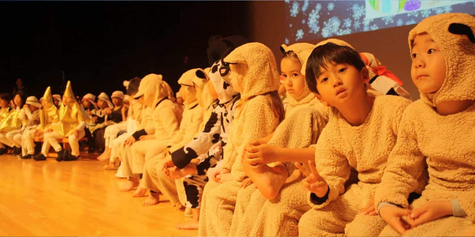 Cute children dressed in animal costumes sitting on stage during a school performance at World Schools.