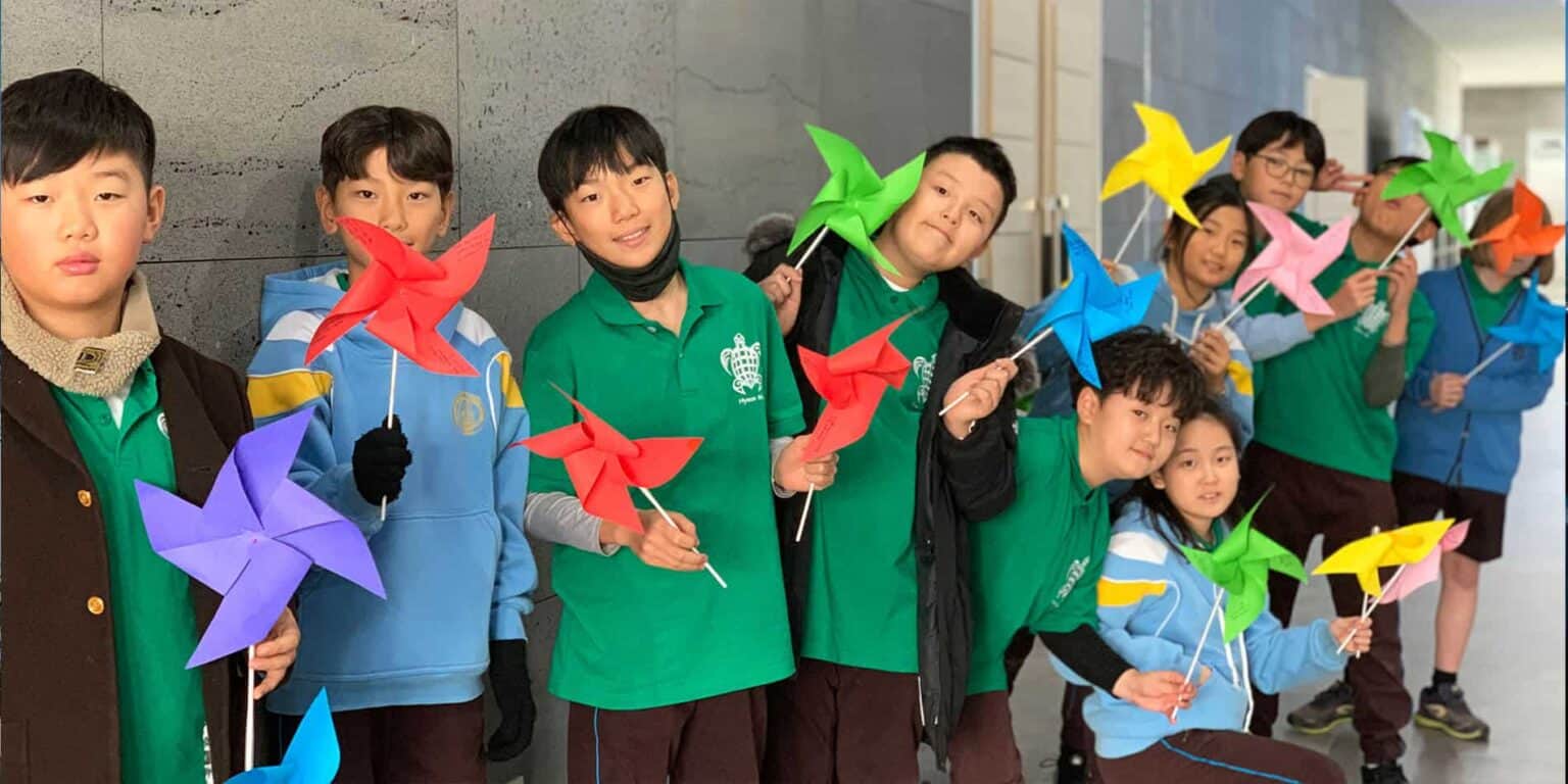 Colorful windmill paper crafts by diverse students at World Schools, promoting creativity and multicultural learning.