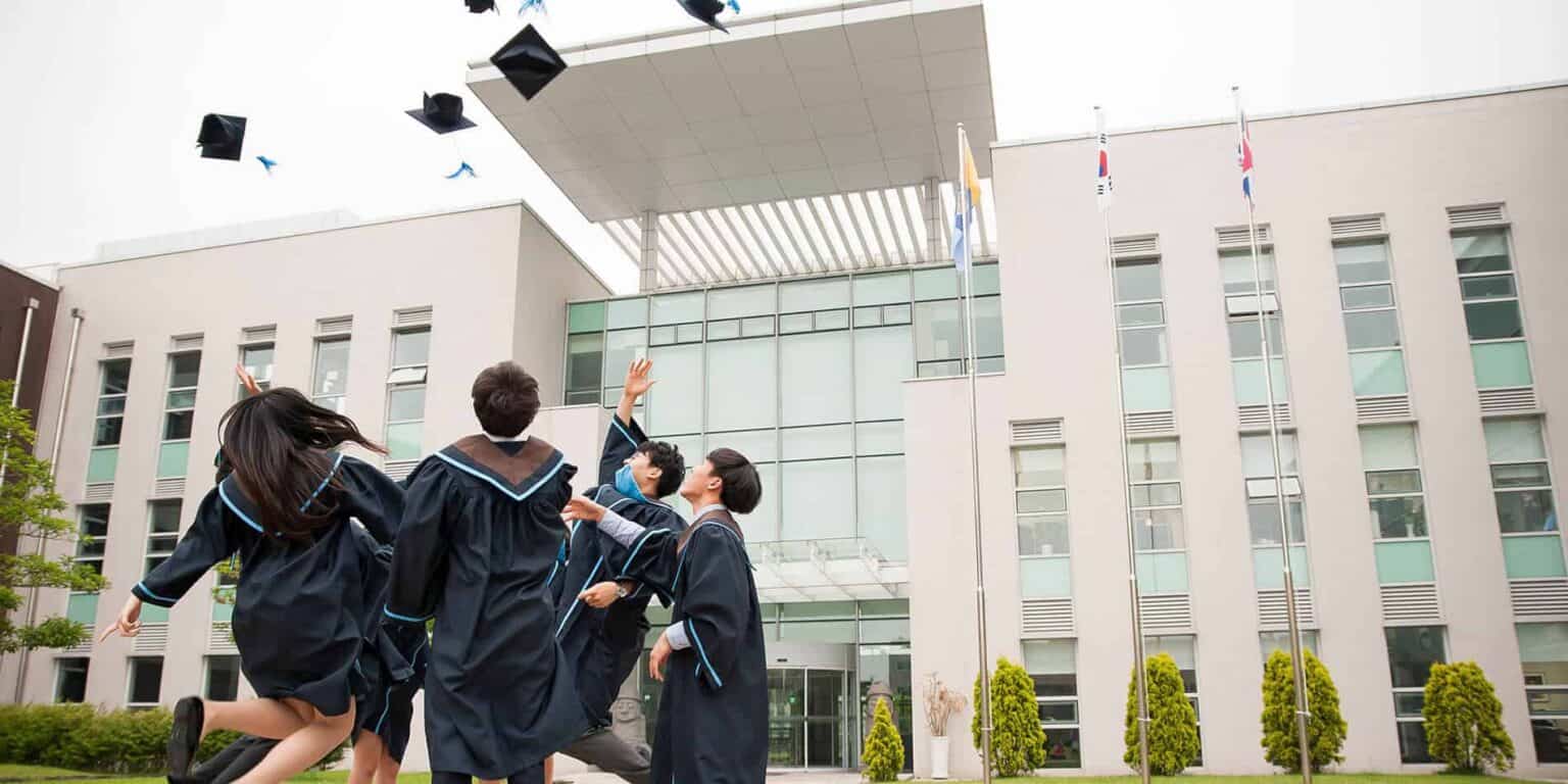 Students celebrating graduation outside a modern school building for world schools.