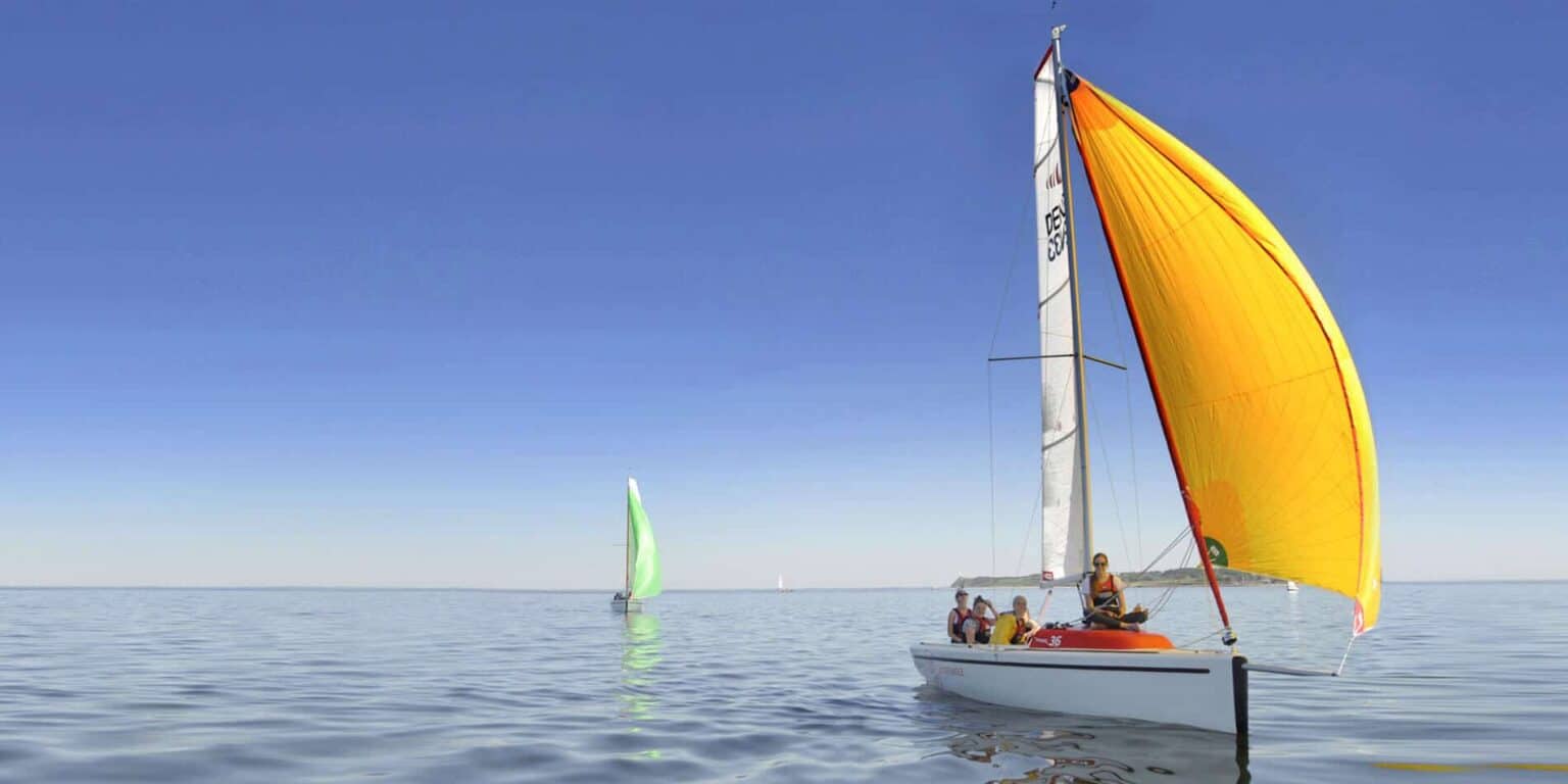 Colorful sailboats on calm water during a sunny day, education-focused outdoor activity at a world school.