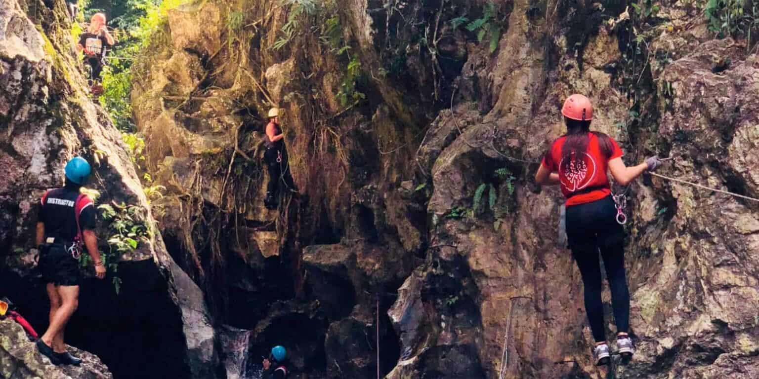 Adventure rock climbing at a nature park with students wearing safety gear and harnesses.