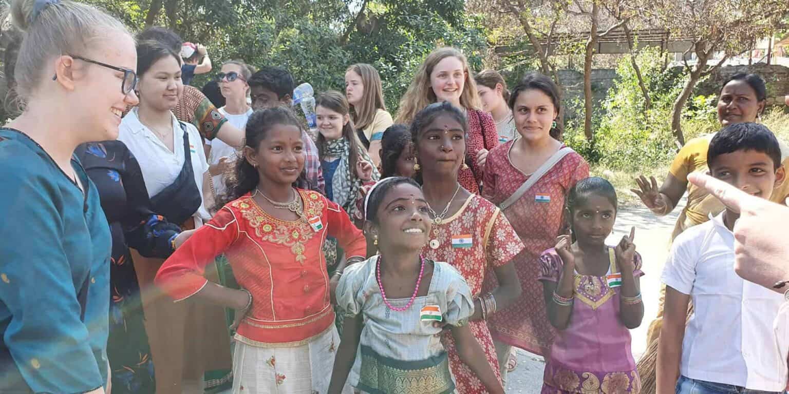 Diverse group of children and teachers engaging outdoors, promoting global education and cultural exchange.