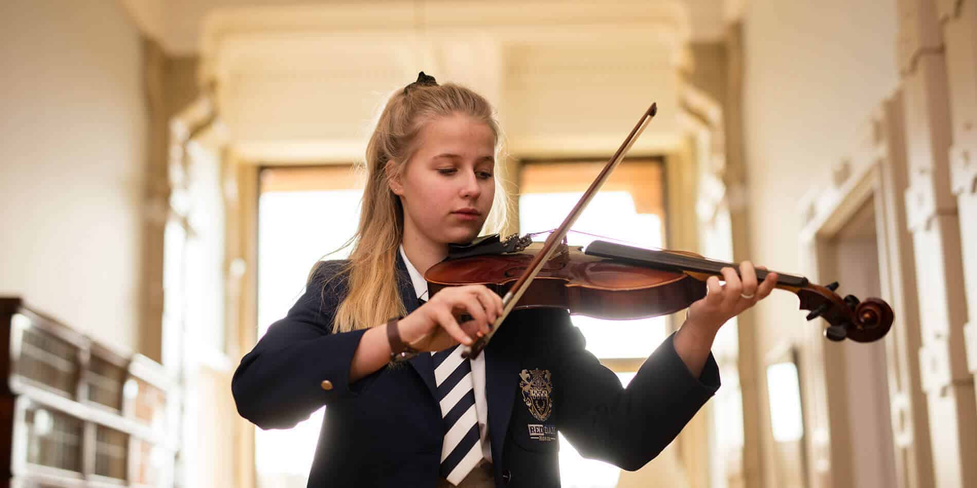 Young girl playing violin in school Music class.