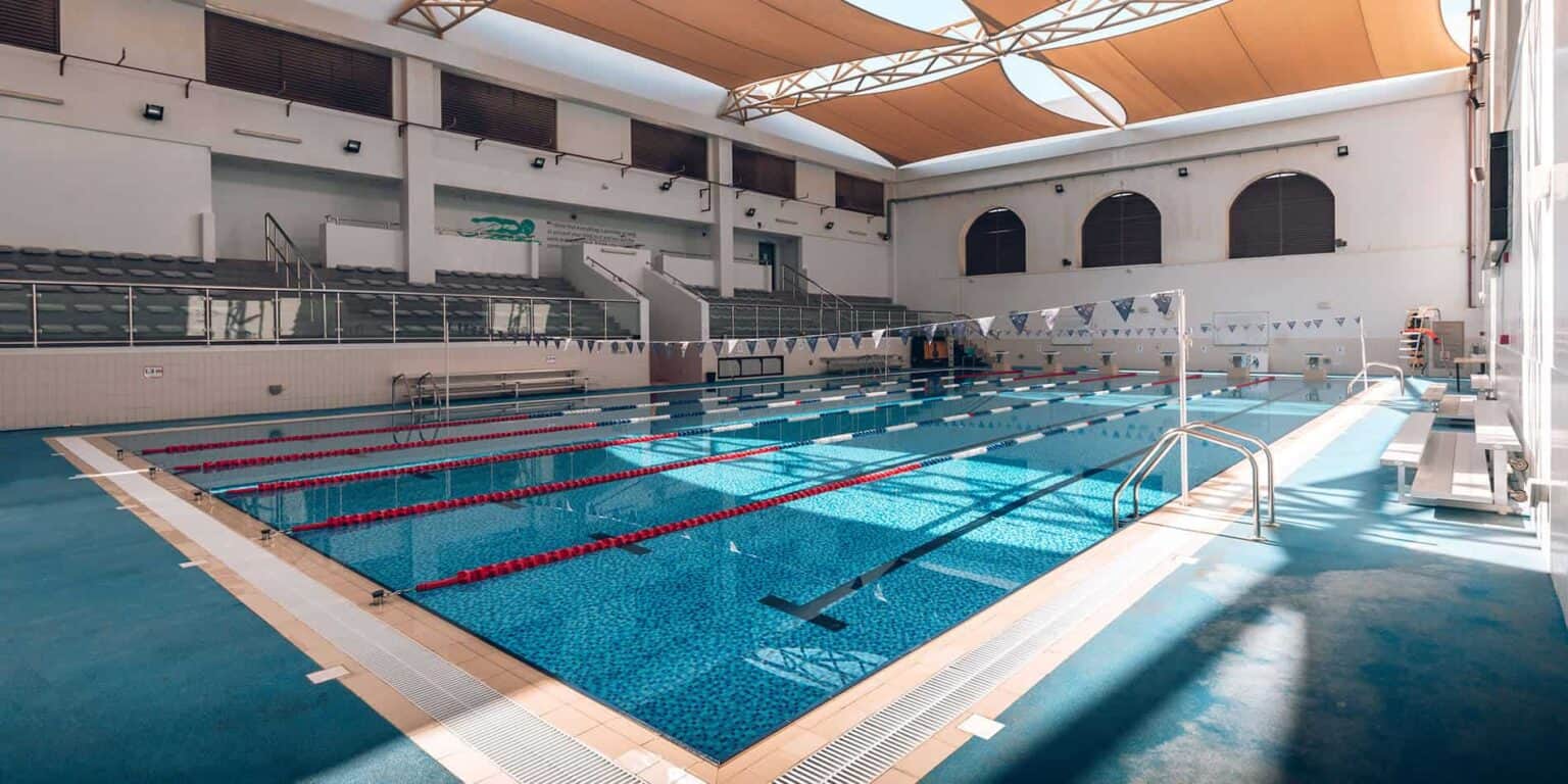 Luminosa piscina cubierta en una moderna instalación escolar, ideal para el desarrollo atlético y el recreo de los alumnos.