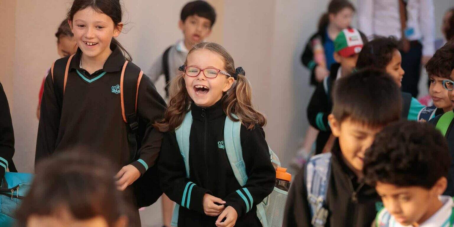Niños sonriendo y riendo en la escuela, grupo diverso de alumnos, entorno de aprendizaje vibrante, comunidad educativa de los Colegios del Mundo.